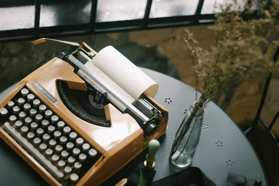 Een vintage Olivetti-typemachine op een tafel naast een vaas.