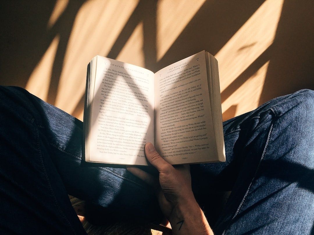 Persoon leest een opengeslagen boek in warme, rustige zonnestralen